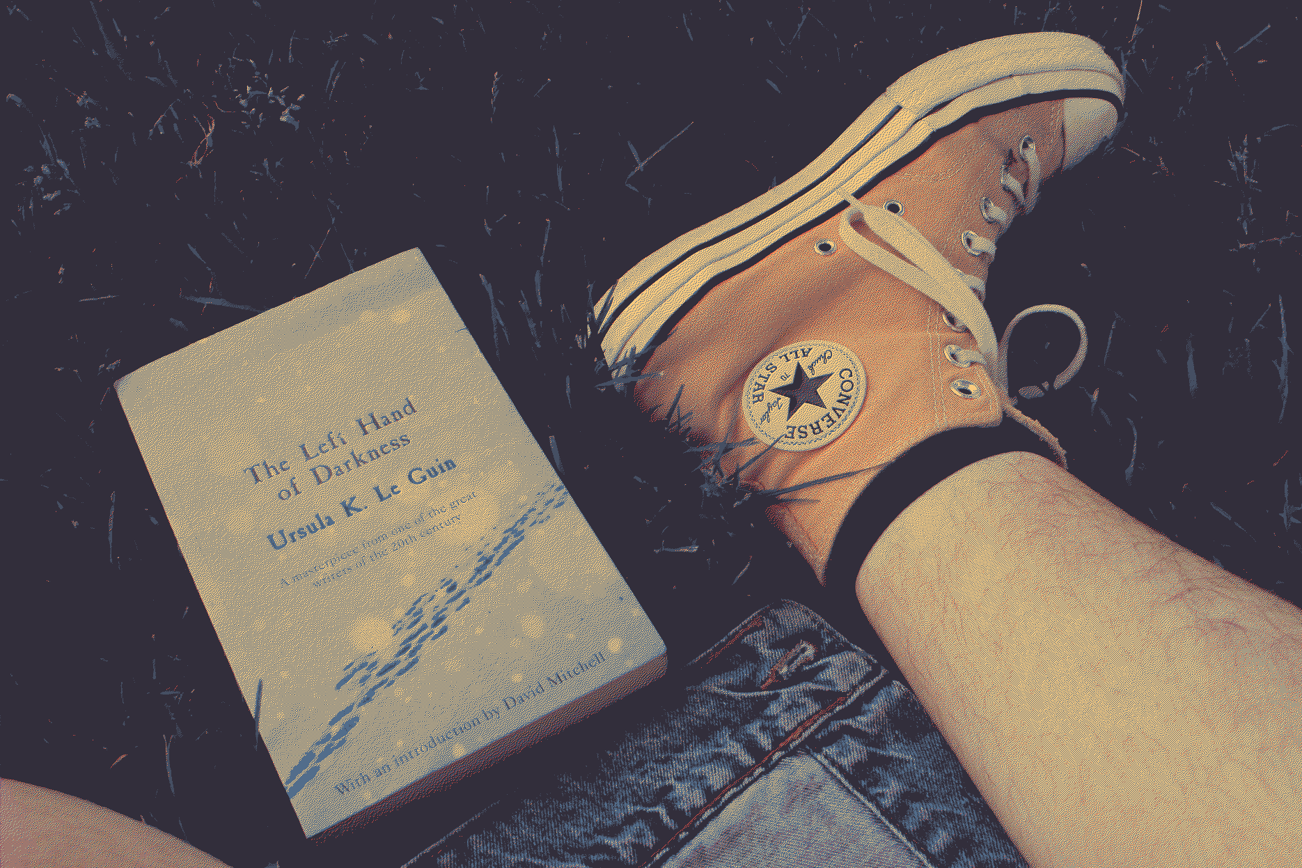 A photo of the book I was reading while at the park, The Left Hand of Darkness by Ursula Le Guin, and my foot wearing a yellow converse shoe next to it.